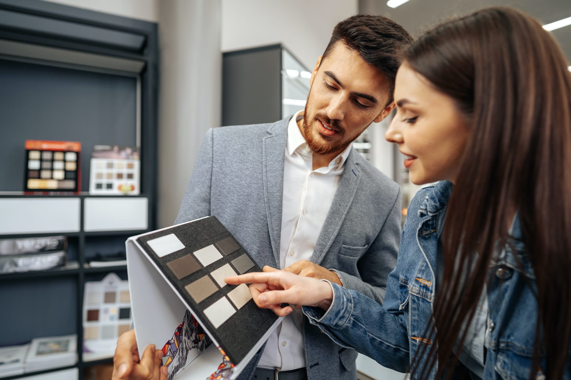 Salesman shows color swatches to lady customer for new kitchen furniture